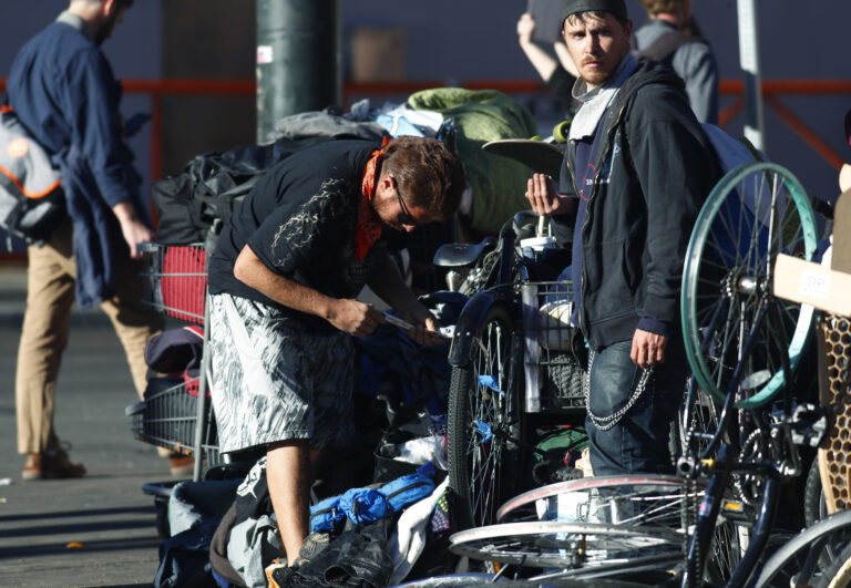 Unidentified men pack up their belongings during a sweep of homeless people who were living on the walks surrounding a shelter near the baseball stadium Tuesday, Nov. 15, 2016, in downtown Denver.  new report from The National Law Center on Homelessness and Poverty said Tuesday, Nov. 15, 2016, that cities nationwide such as Denver are enacting more policies that criminalize homelessness. (AP Photo/David Zalubowski) (AP)