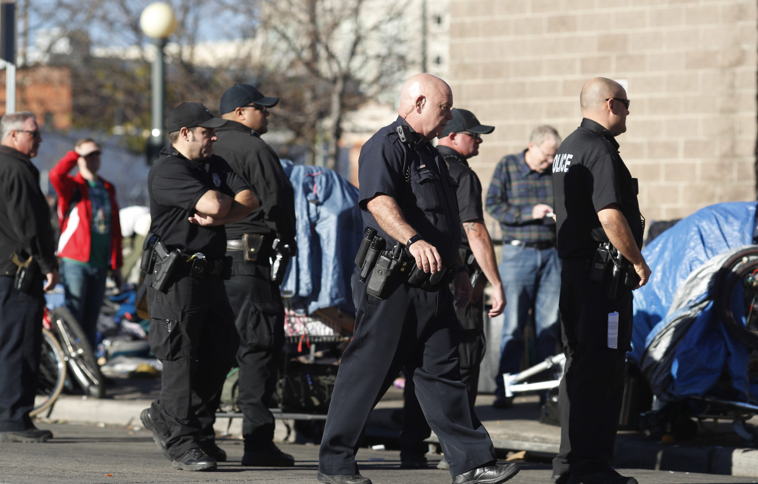 Denver Police Department officers keep watch during a sweep of homeless people who were living on the walks surrounding a shelter near the baseball stadium Tuesday, Nov. 15, 2016, in downtown Denver. A new report from The National Law Center on Homelessness and Poverty said Tuesday, Nov. 15, 2016, that cities nationwide such as Denver are enacting more policies that criminalize homelessness. (AP Photo/David Zalubowski) (AP)