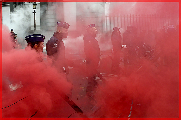 Belgian police officers stand guard amid red smoke after protesters threw coloured smoke grenades during a demonstration in Brussels organised by the Belgian military unions to protest against a decision by the government to raise the retirement age for soldiers to 63 on November 15, 2016. / AFP / JOHN THYS        (Photo credit should read JOHN THYS/AFP/Getty Images) (Afp/getty Images)