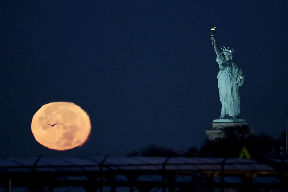 The supermoon appears near the Statue of Liberty, Monday, Nov. 14, 2016, in New York. Monday's supermoon, a phenomenon that happens when the moon makes a close pass at the earth, is the closest to earth since 1948. (AP Photo/Julio Cortez) (AP)