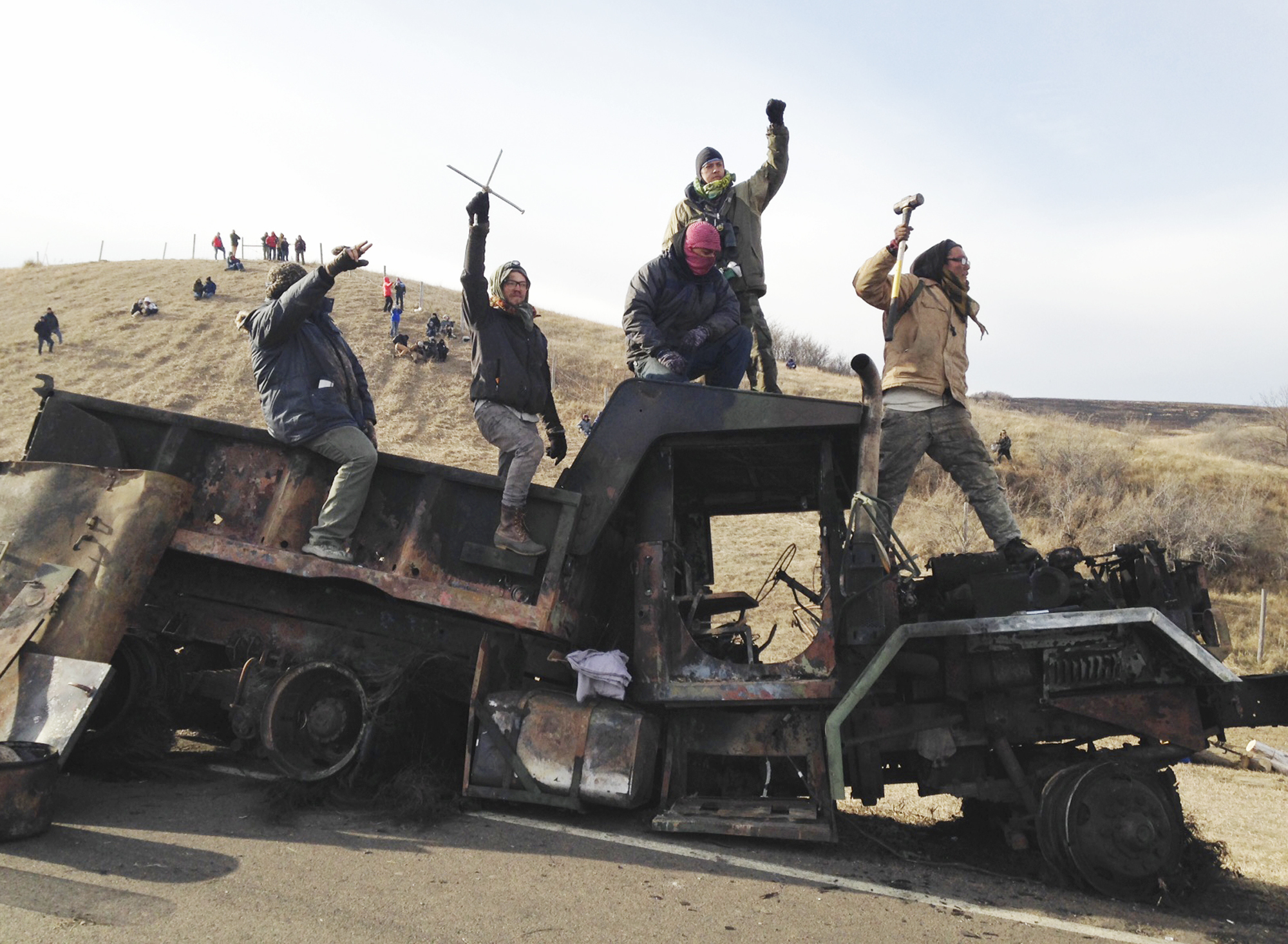 FILE - In this Monday, Nov. 21, 2016, file photo, protesters against the Dakota Access oil pipeline stand on a burned-out truck near Cannon Ball, N.D., that they removed from a long-closed bridge a day earlier on a state highway near their camp in southern North Dakota. President-elect Donald Trump holds stock in the company building the disputed Dakota Access oil pipeline, and pipeline opponents warn that Trump’s investments could undercut any decision he makes on the $3.8 billion project as president. (AP Photo/James MacPherson, File) (AP)