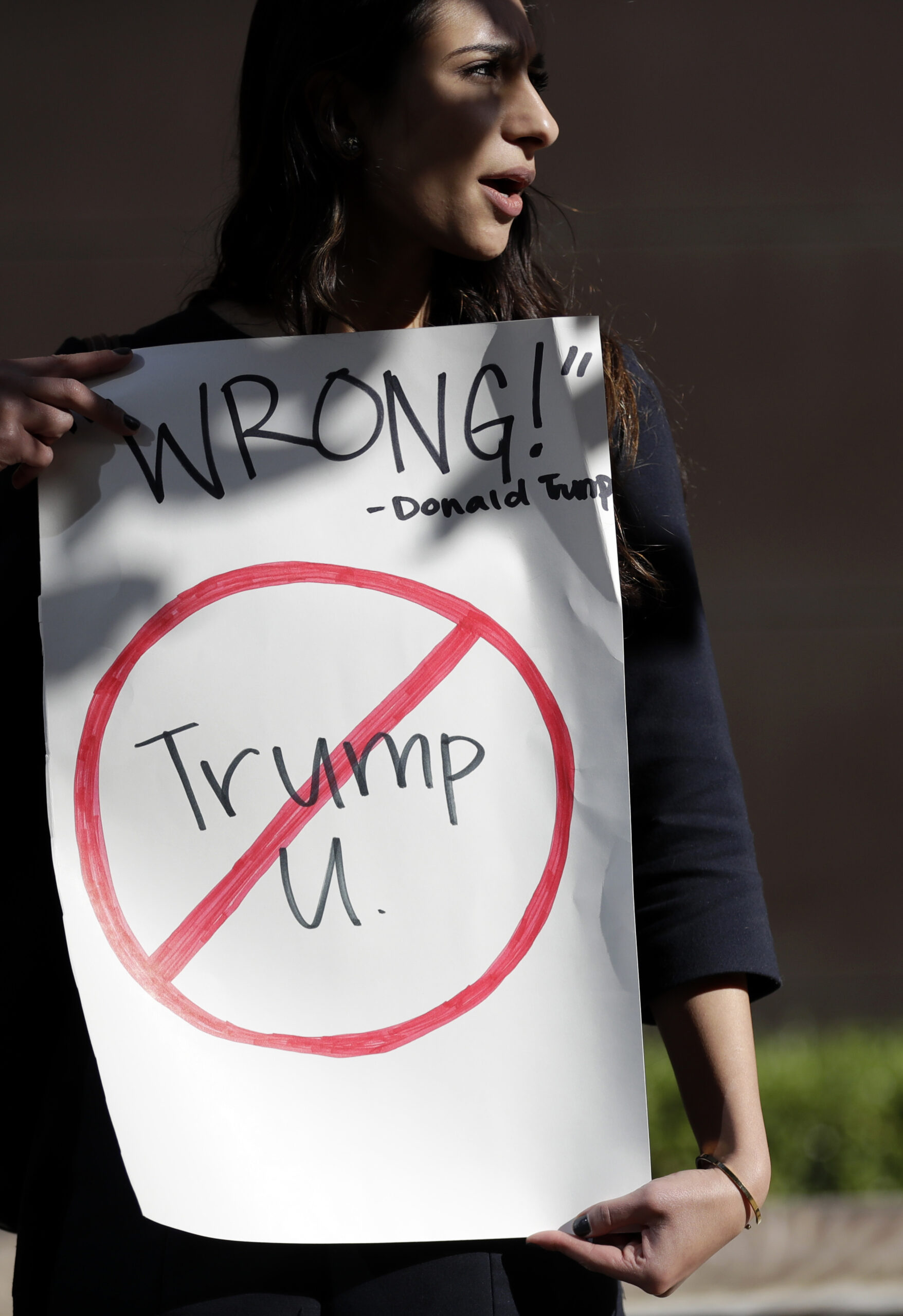 Senya Merchant holds a sign against President-elect Donald Trump's now-defunct Trump University Friday, Nov. 18, 2016, in San Diego. (AP)