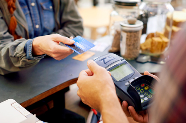 Shot of a customer paying for their order with a credit card machine in a cafe (Getty/PeopleImages)