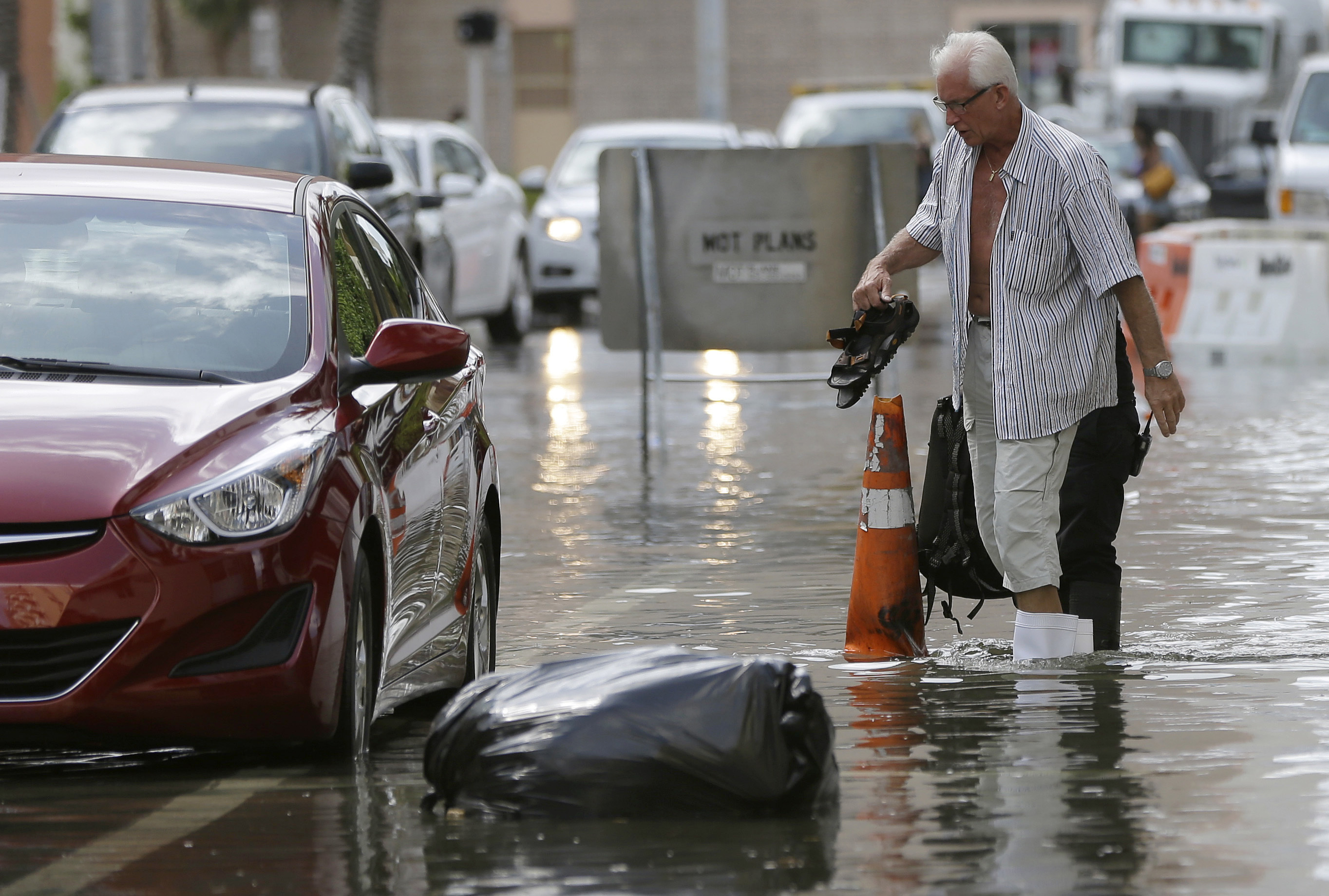 FILE - In this Sept. 30, 2015 file photo, a hotel guest carries his shoes as he is escorted to his car along in Miami Beach, Fla. The street flooding was in part caused by high tides due to the lunar cycle, according to the National Weather Service. A new scientific report finds man-made climate change played some kind of role in two dozen extreme weather events around the world in 2015. But it also detected no global warming fingerprints in a handful of other weird weather instances. (AP Photo/Lynne Sladky, File) (AP)
