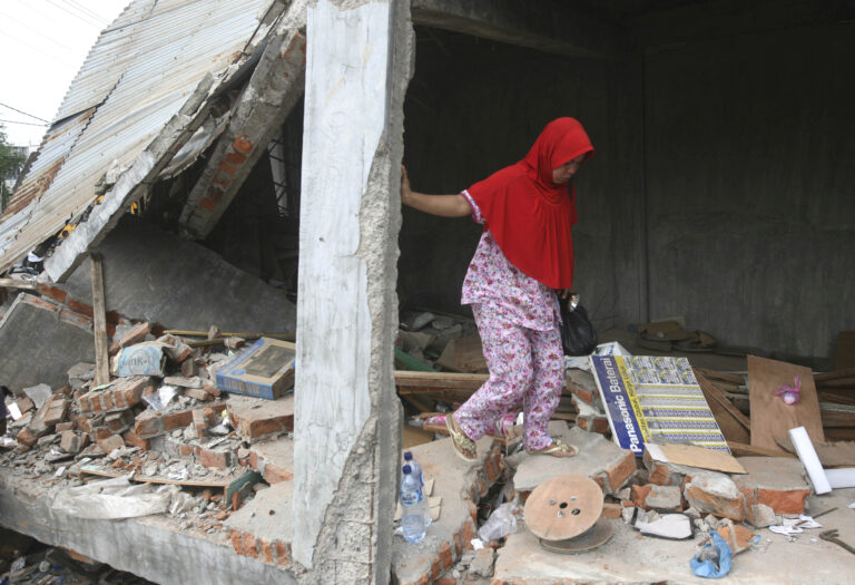 Earthquake survivor Fakriyah tries to balance herself as she walks on the rubble at her shop damaged during Wednesday's earthquake in Tringgading, Aceh province, Indonesia, Friday, Dec. 9, 2016. Over a hundred people were killed in the quake that hit the northeast of the province on Sumatra before dawn Wednesday. Hundreds of people were injured and thousands buildings destroyed or heavily damaged. (AP Photo/Binsar Bakkara) (AP)