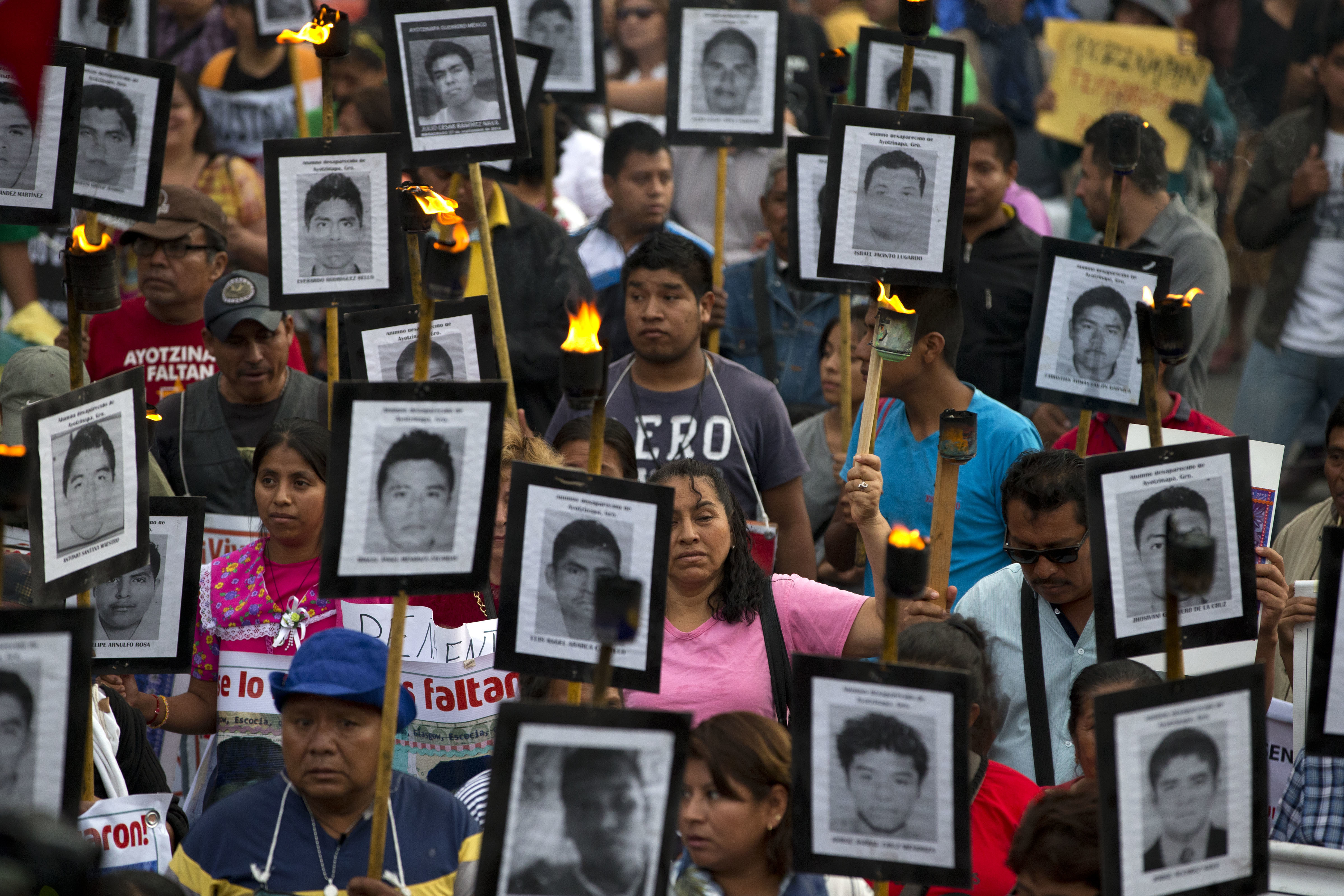 FILE - In this April 26, 2016 file photo, family members and supporters of 43 missing teachers college students carry pictures of the students as they march to demand the case not be closed and that experts' recommendations about new leads be followed, in Mexico City. In Mexico’s ten year war on drugs advances can be seen in places like the violent border city of Ciudad Juarez, where the number of homicides fell when it began a stepped-up policing effort. But those kind of gains haven’t been seen in most other states. (AP Photo/Rebecca Blackwell, File) (AP)