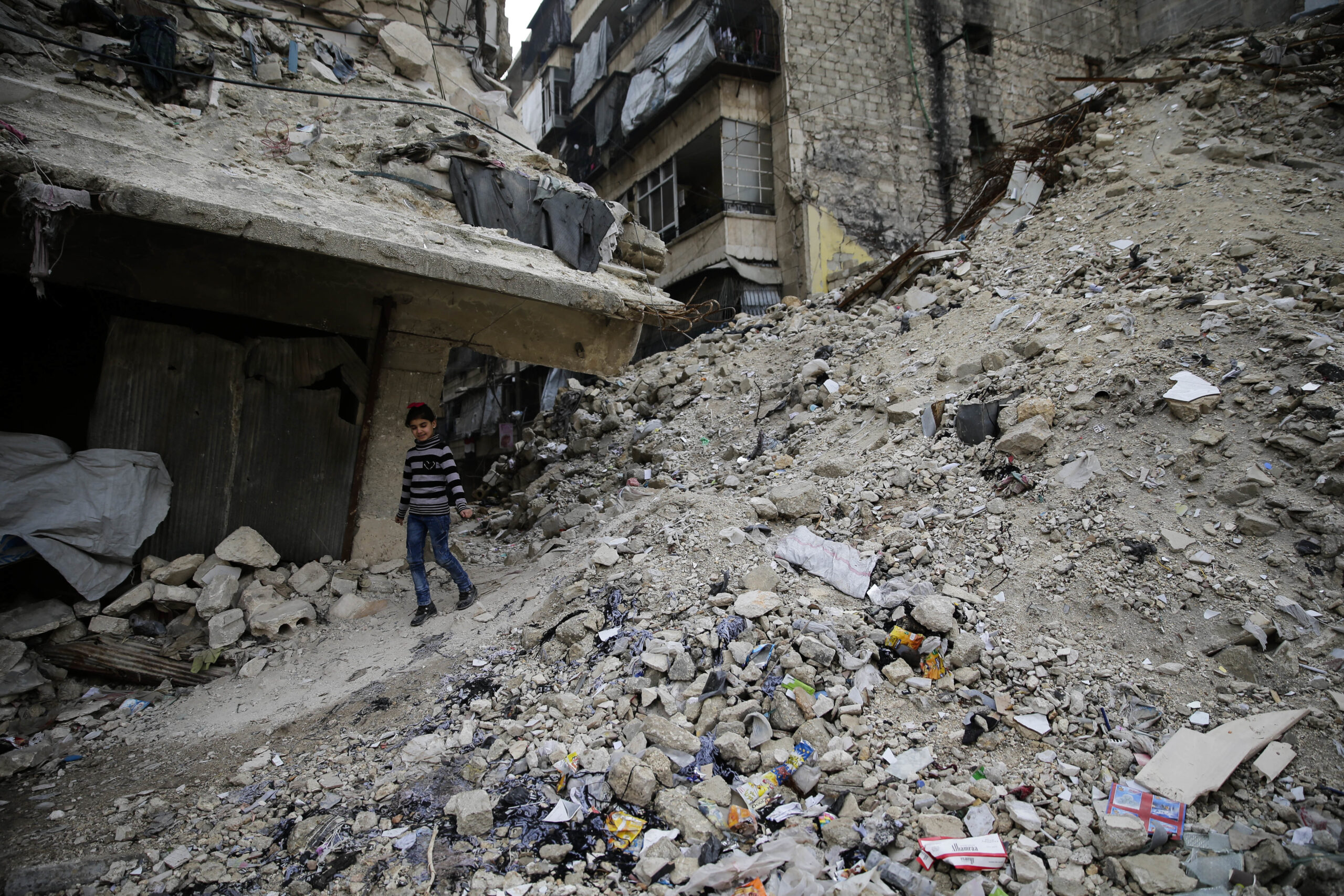 In this Monday, Dec. 5, 2016 photo, a Syrian girl walks amid the wreckage of damaged buildings and shops in the western city of Aleppo, Syria. (AP)