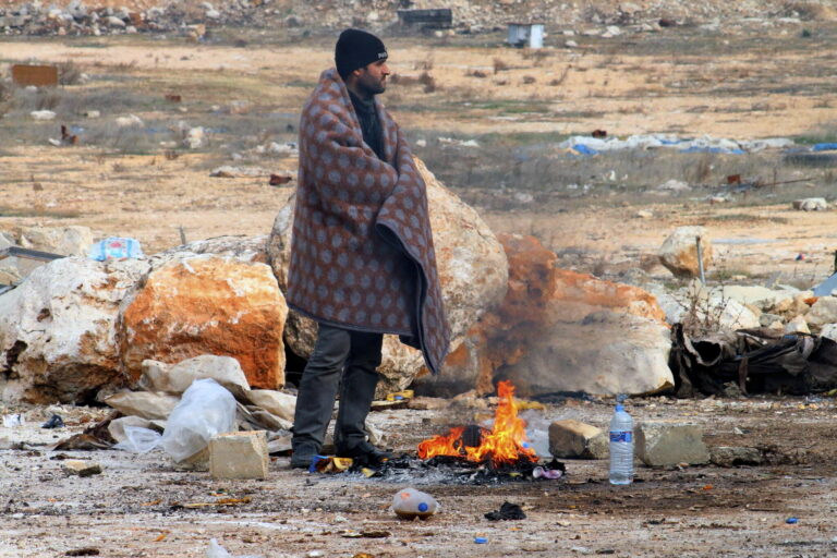 This image released on Friday, Dec. 16, 2016 by Aleppo 24, shows a man of eastern Aleppo standing next to a fire in western rural Aleppo, Syria. As the last holdouts leave the rebel-held enclave in Aleppo, they speak of their love for the city despite witnessing so much destruction and death. Bit by bit over three weeks, the government offensive chipped away at their last refuge. (Aleppo 24 via AP) (AP)