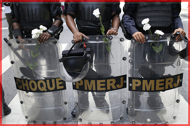 Police officers stand with flowers given to them by demonstrators during a protest against austerity measures outside the state legislature, in Rio de Janeiro, Brazil, Monday, Dec. 12, 2016. Police, firefighters and school teachers are among the workers for Brazil’s Rio de Janeiro state protesting against government austerity measures being considered by lawmakers. (AP Photo/Silvia Izquierdo) (AP)