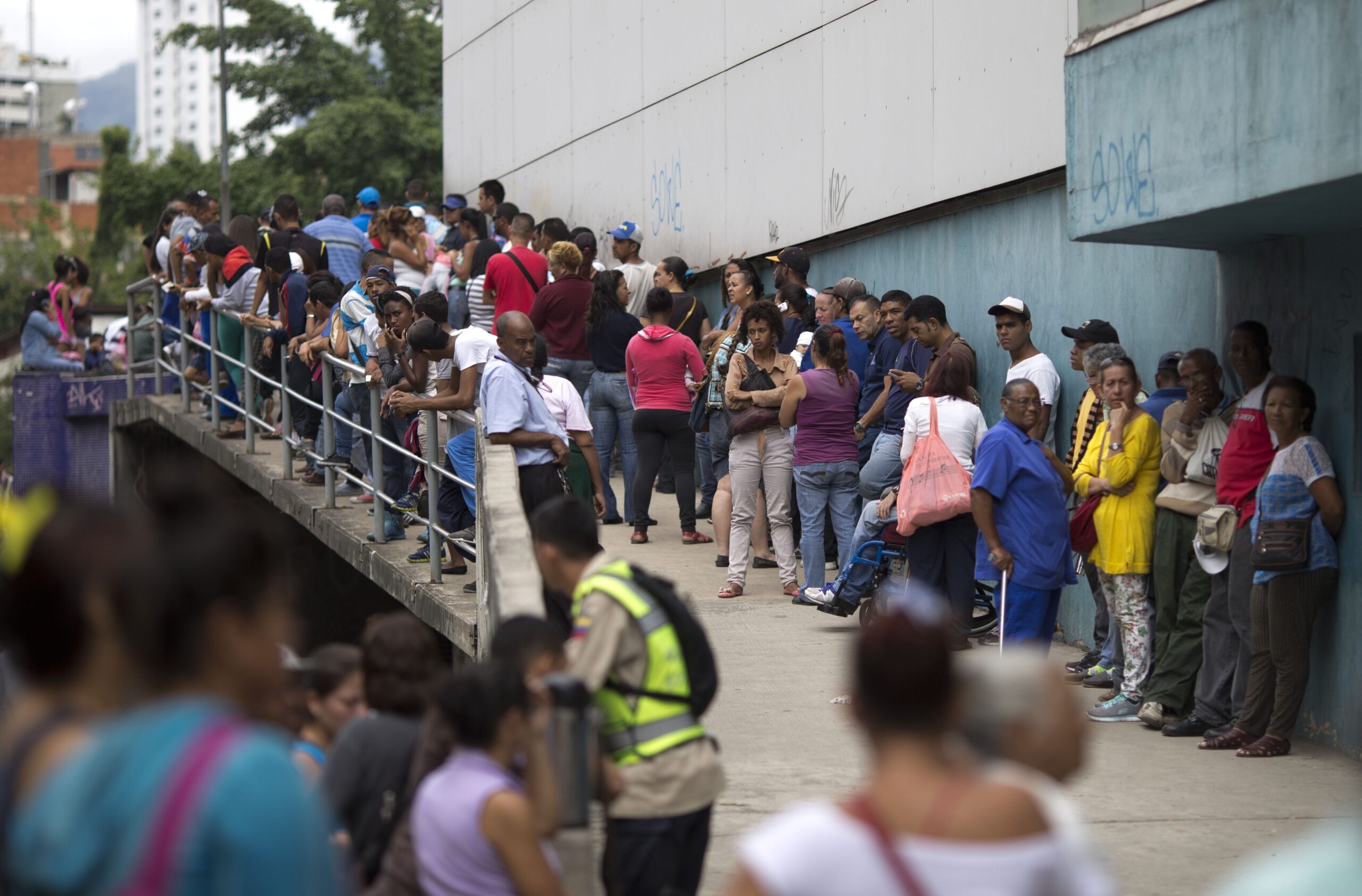 In this Nov. 18, 2016 photo, people wait outside a supermarket to buy government subsided food in Caracas, Venezuela. As domestic production dries up in Venezuela, the state has given itself the role of importing nearly all the country's food. (AP)