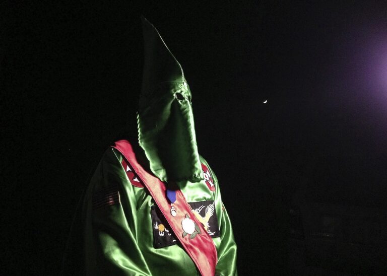 In this photo taken Friday, Dec. 2, 2016, a robed and masked Ku Klux Klansmen stands on a muddy dirt road during an interview near Pelham, N.C. The KKK and other white extremist groups don't like being called "white supremacists," a phrase that dates to the earliest days of white racist movements in the United States. () (AP Photo/Jay Reeves)