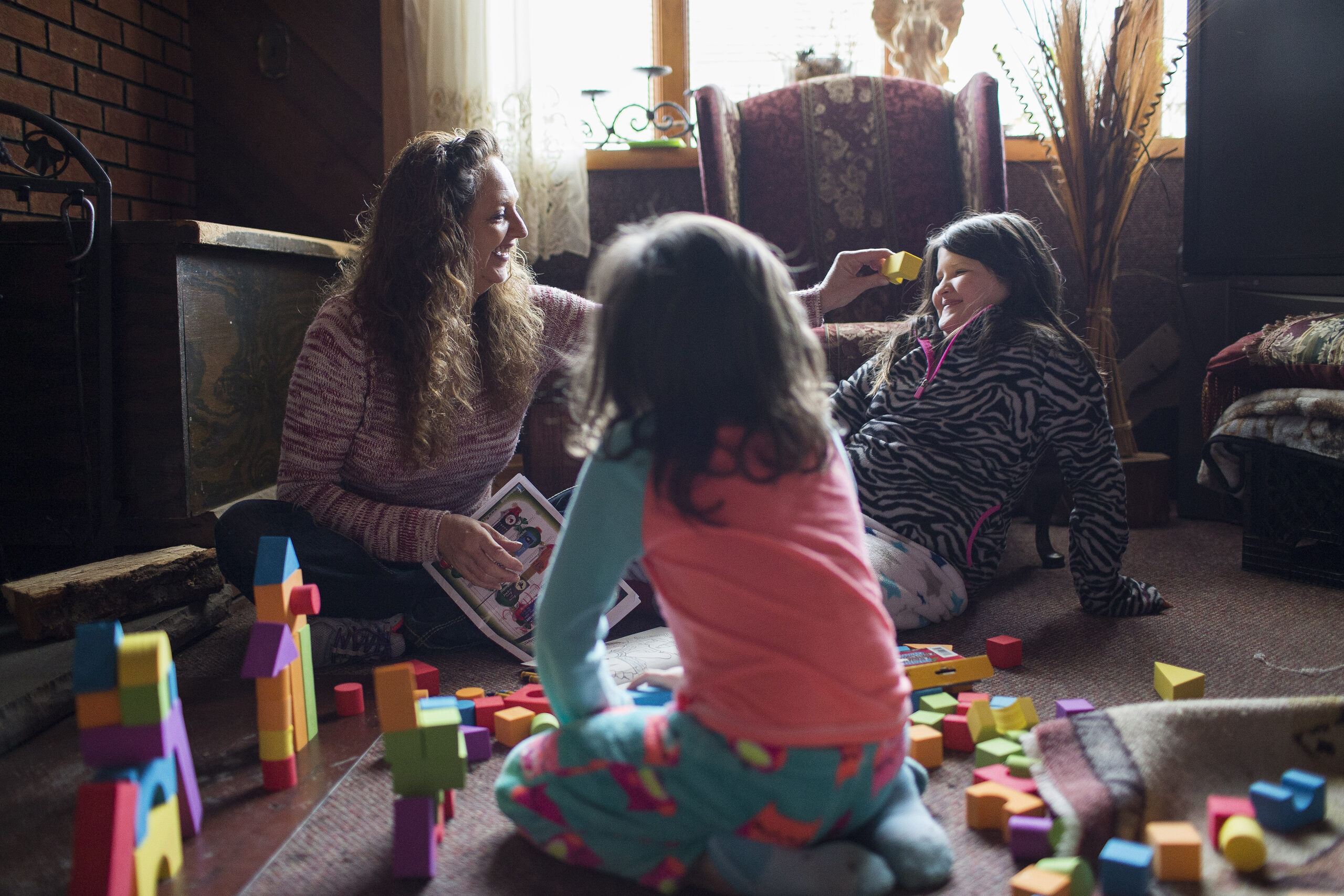 In this Monday, Dec. 19, 2016, photo, Donna Dye, who is unemployed and whose husband is disabled, plays with her two granddaughters, Lilly, left, and Chloe, at her home where she cares for them, in Minnie, Ky. Dye and her husband have been fighting the federal government to keep his Social Security disability checks after a local lawyer who helped them became the subject of a federal fraud investigation. (AP Photo/David Stephenson) (AP)