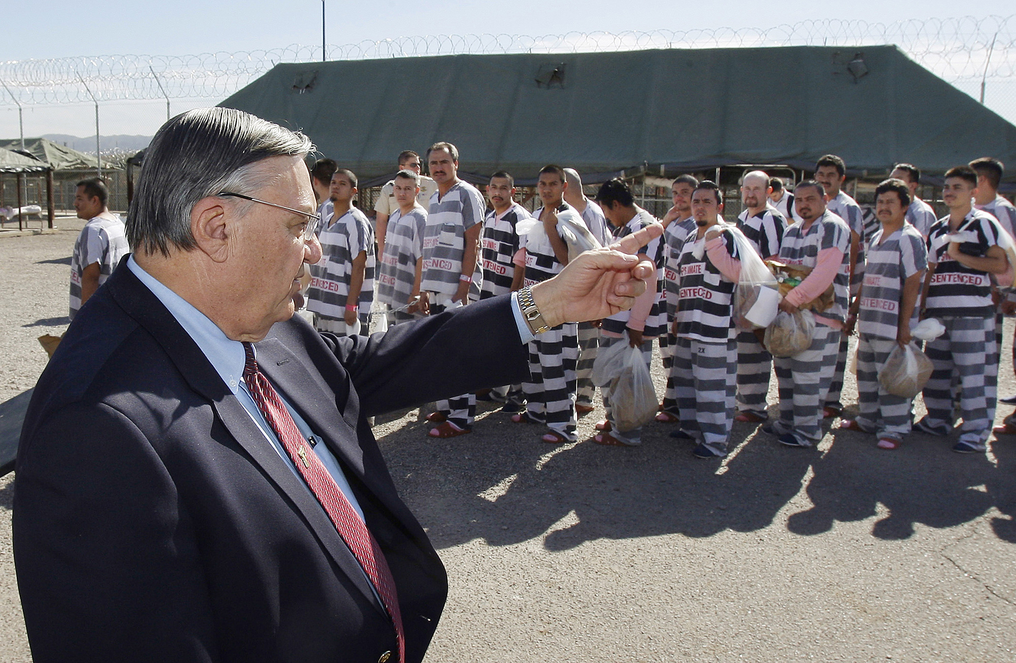 FILE - In this Feb. 4, 2009, file photo, Maricopa County Sheriff Joe Arpaio, left, orders approximately 200 convicted illegal immigrants handcuffed together and moved into a separate area of Tent City, for incarceration until their sentences are served and they are deported to their home countries, in Phoenix. (AP Photo/Ross D. Franklin, File)