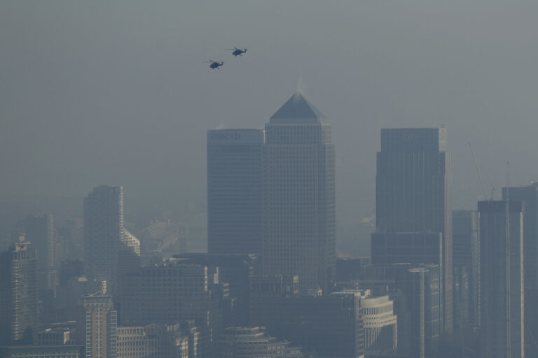 Helicopters fly through pollution over the Canary Wharf business district through a window in a viewing area of the 95-storey skyscraper The Shard, the tallest building in Britain at 309.6 metres, in London, Thursday, Jan. 19, 2017. Eight London boroughs issued high pollution warnings Thursday. (AP Photo/Matt Dunham) (AP)