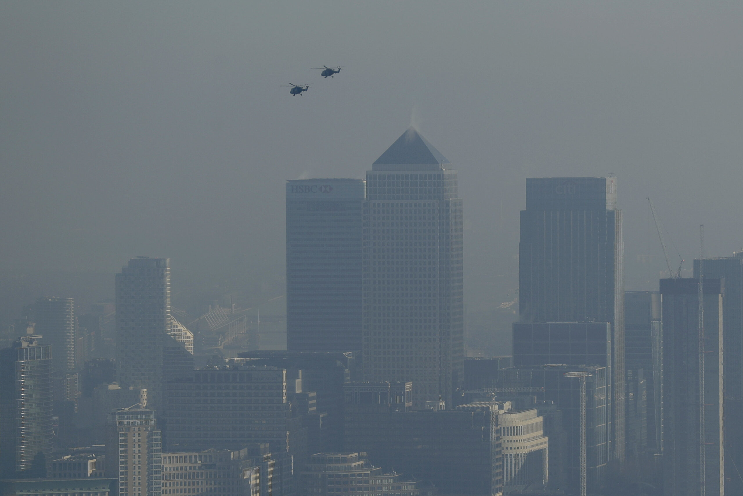 Helicopters fly through pollution over the Canary Wharf business district through a window in a viewing area of the 95-storey skyscraper The Shard, the tallest building in Britain at 309.6 metres, in London, Thursday, Jan. 19, 2017. Eight London boroughs issued high pollution warnings Thursday. (AP Photo/Matt Dunham) (AP)