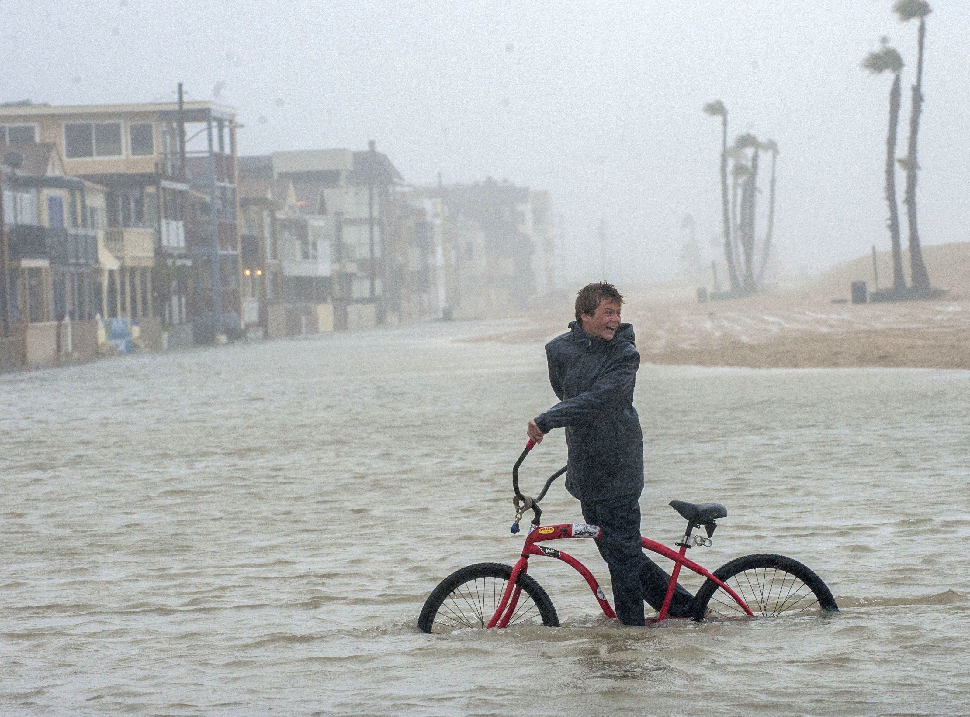 Jake Hart, 13, plays in the rising floodwater during a storm in Seal Beach, Calif., Sunday, Jan. 22, 2017. The heavy downpour on Sunday drenched Orange County in one of the heaviest storms of the year. Fast-moving floodwaters swept through California mountain communities and residents fled homes below hillsides scarred by wildfires as the third in the latest series of storms brought a deluge Sunday and warnings about damaging mudslides. (Ana Venegas/The Orange County Register via AP) (AP)