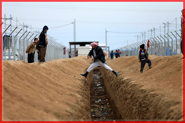 Displaced people who fled from the clashes in Mosul jump across a ditch at Khazer camp, Iraq, January 25, 2017. REUTERS/Alaa Al-Marjani - RTSXC12 (© Alaa Al-marjani / Reuters)