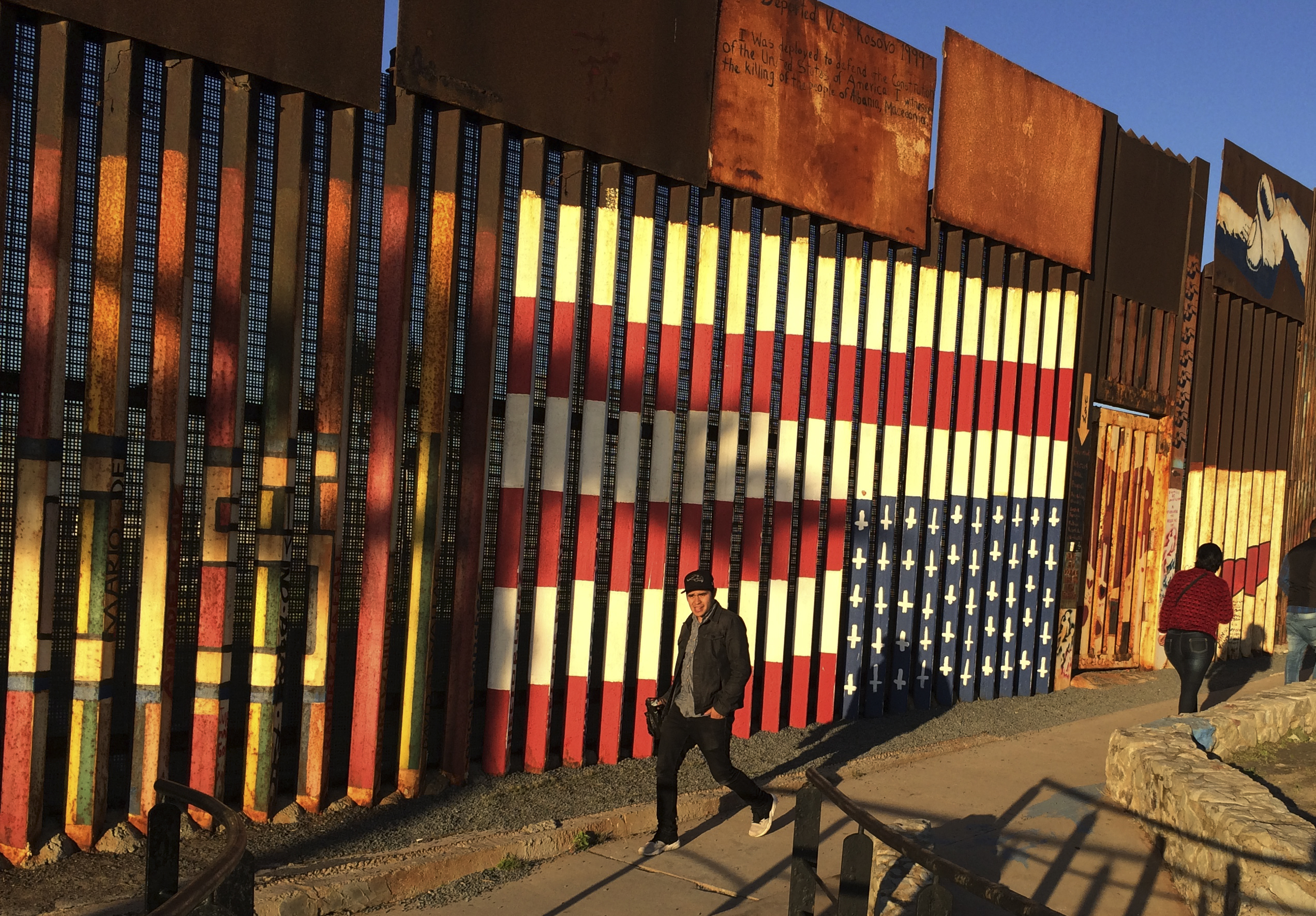 People pass graffiti along the border structure in Tijuana, Mexico, Wednesday, Jan. 25, 2017. President Donald Trump moved aggressively to tighten the nation's immigration controls Wednesday, signing executive actions to jumpstart construction of his promised U.S.-Mexico border wall and cut federal grants for immigrant-protecting "sanctuary cities." () (AP Photo/Julie Watson)