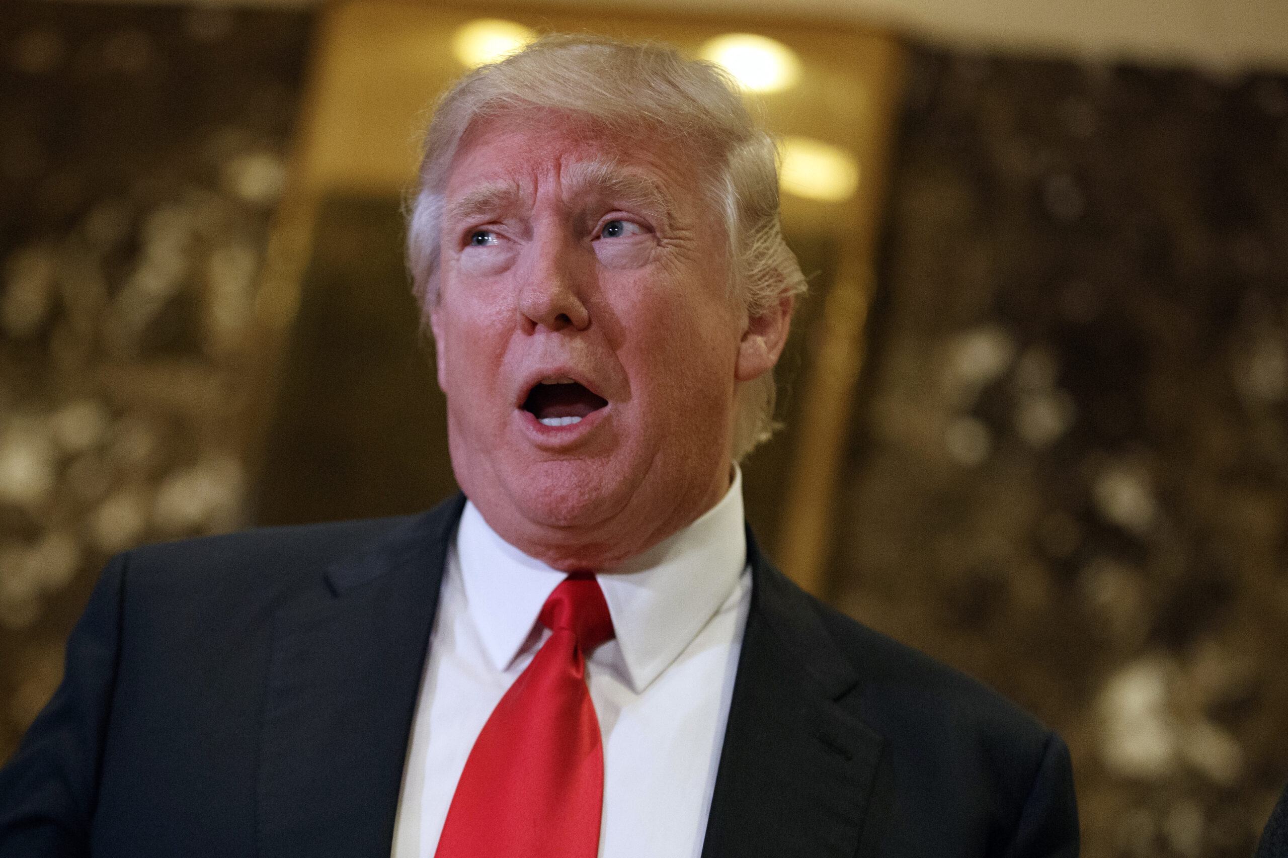 In this Jan. 13, 2017, photo, President-elect Donald Trump speaks with reporters in the lobby of Trump Tower in New York. Trump’s meetings this week with CEOs seeking federal approval for major mergers are raising red flags for ethics lawyers concerned that about the possible erosion of a firewall between the regulators tasked with approving the billion-dollar deals and the White House. (AP Photo/Evan Vucci) (AP)