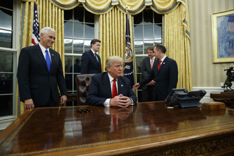 Vice President Mike Pence, left, watches as President Donald Trump prepares to sign his first executive order, Friday, Jan. 20, 2017, in the Oval Office of the White House in Washington. (AP Photo/Evan Vucci) (AP)