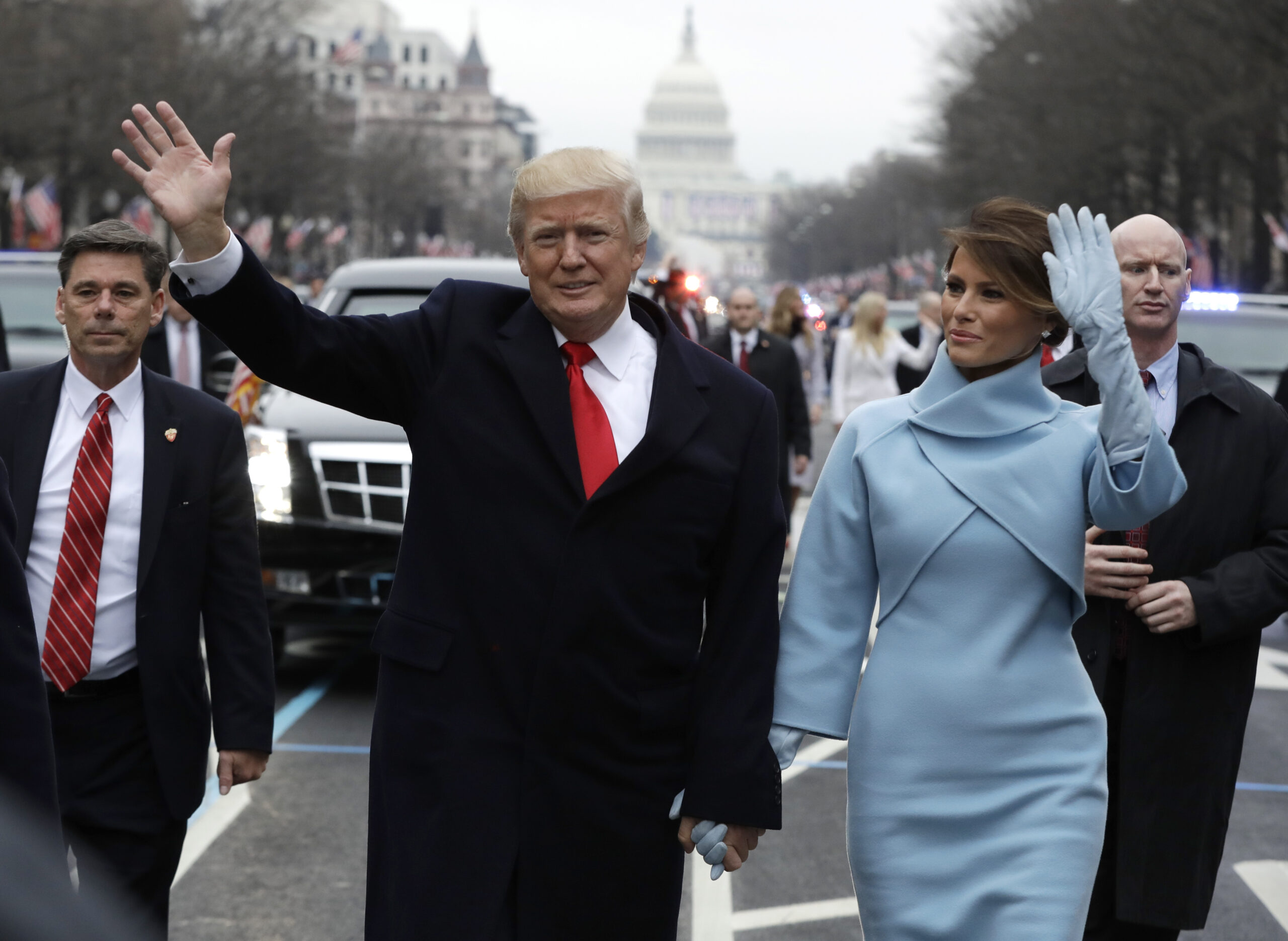 President Donald Trump waves as he walks with first lady Melania Trump during the inauguration parade on Pennsylvania Avenue in Washington, Friday, Jan. 20, 2016. (AP Photo/Evan Vucci, Pool)