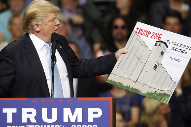 U.S. Republican presidential candidate Donald Trump holds a sign supporting his plan to build a wall between the United States and Mexico that he borrowed from a member of the audience at his campaign rally in Fayetteville, North Carolina March 9, 2016. Trump was interrupted repeatedly by demonstrators during his rally.    REUTERS/Jonathan Drake - RTSA418 (Reuters)