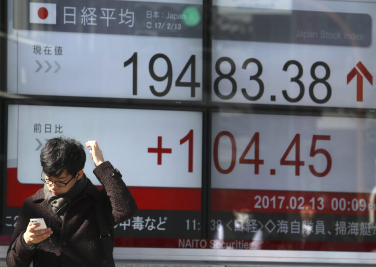 A man uses a mobile phone in front of an electronic stock indicator of a securities firm in Tokyo, Monday, Feb. 13, 2017.   (AP Photo/Shizuo Kambayashi) (AP)