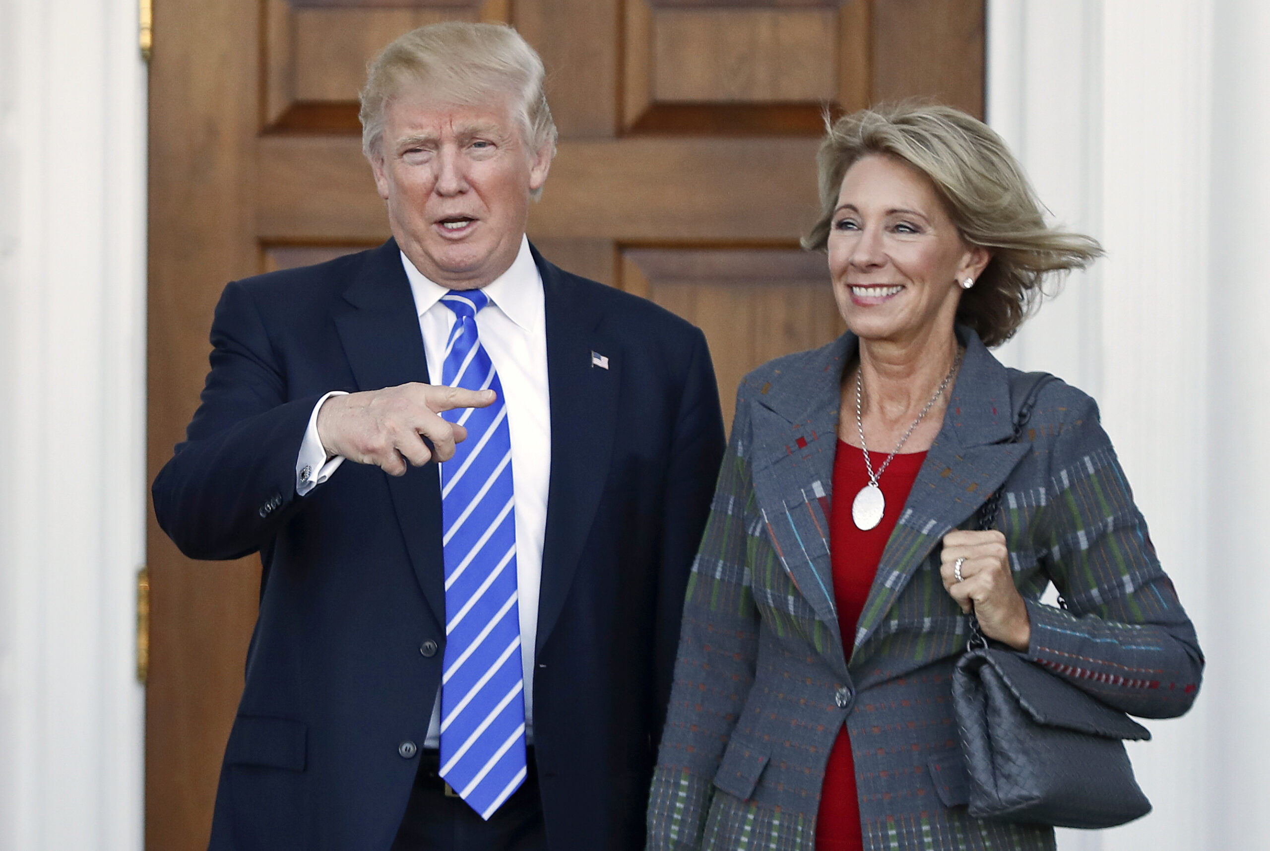 FILE – In this Nov. 19, 2016 file photo, President-elect Donald Trump, left, and Betsy DeVos, right, pose for photographs at Trump National Golf Club Bedminster's clubhouse in Bedminster, N.J. Republican Ohio Gov. John Kasich wrote a Jan. 24, 2017, letter urging confirmation of DeVos, Trump's education secretary nominee, without mentioning the significant unpaid fine owed to Ohio by a now-defunct political action committee she controlled. () (AP Photo/Carolyn Kaster, File)