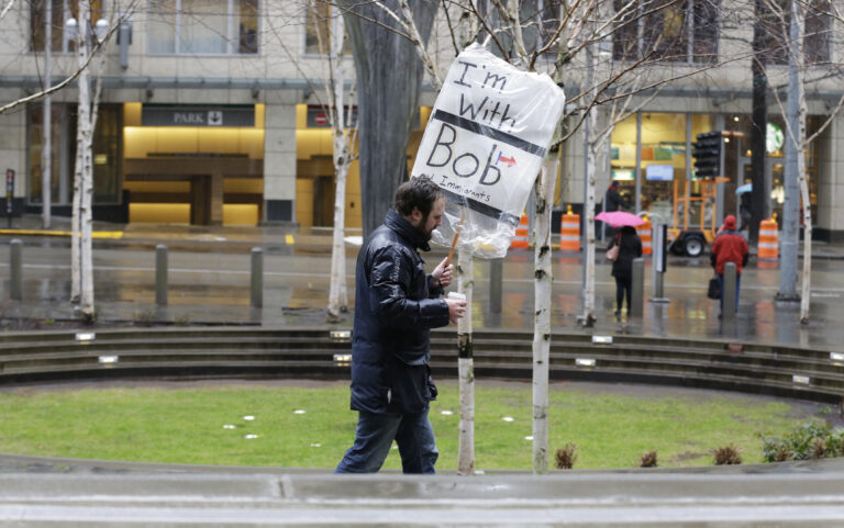 A person walks outside the federal courthouse in Seattle carrying a sign that reads "I'm with Bob and Immigrants," in reference to Washington state Attorney General Bob Ferguson, Friday, Feb. 3, 2017, during a hearing in federal court. A U.S. judge on Friday temporarily blocked President Donald Trump's ban on people from seven predominantly Muslim countries from entering the United States after Washington state and Minnesota urged a nationwide hold on the executive order that has launched legal battles across the country. (AP Photo/Ted S. Warren) (AP)