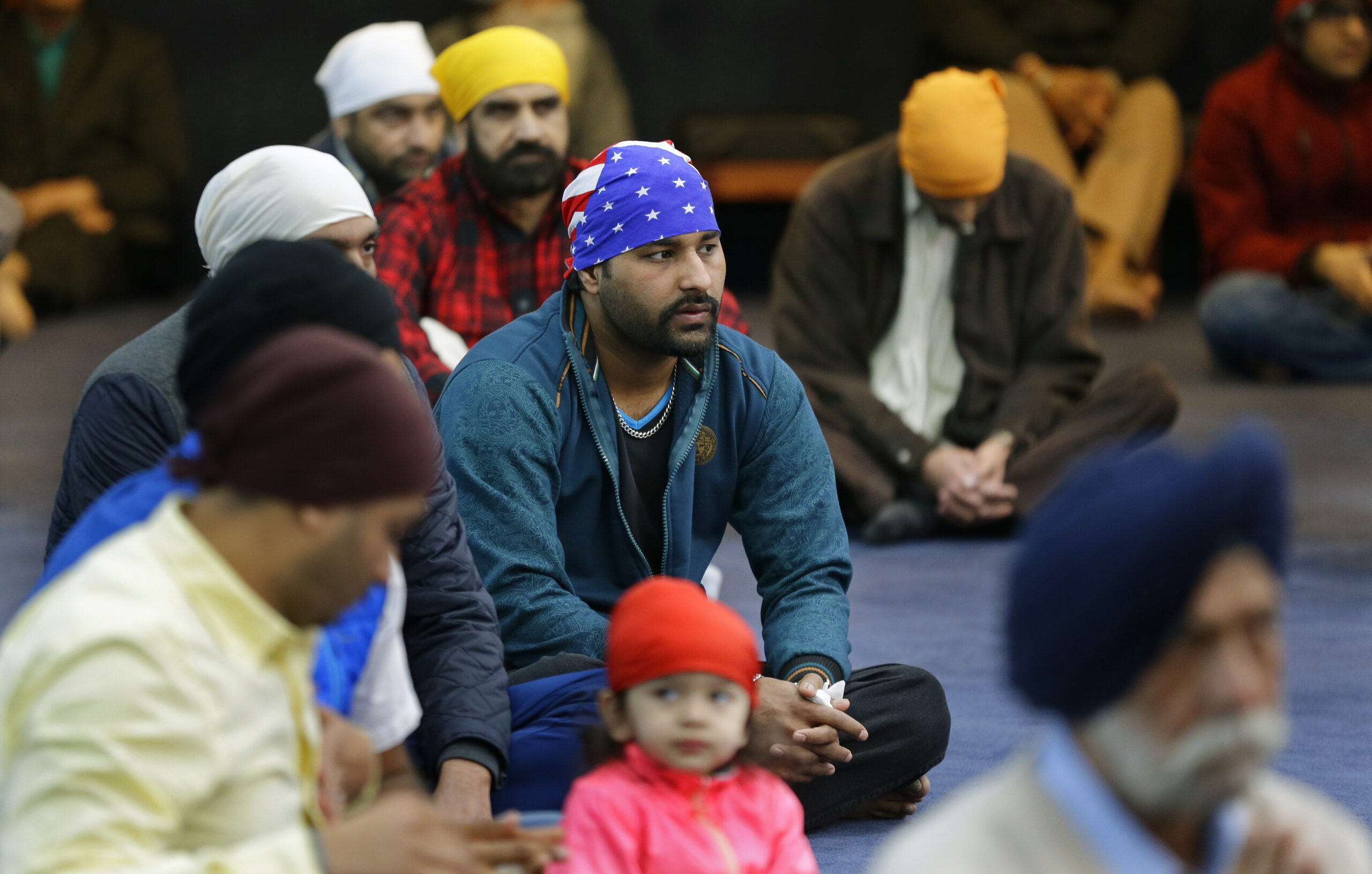 Men, including one wearing a head covering with the stars and stripes of the U.S. flag, attend Sunday services at the Gurudwara Singh Sabha of Washington, a Sikh temple in Renton, Wash., Sunday, March 5, 2017, south of Seattle. (AP Photo/Ted S. Warren)