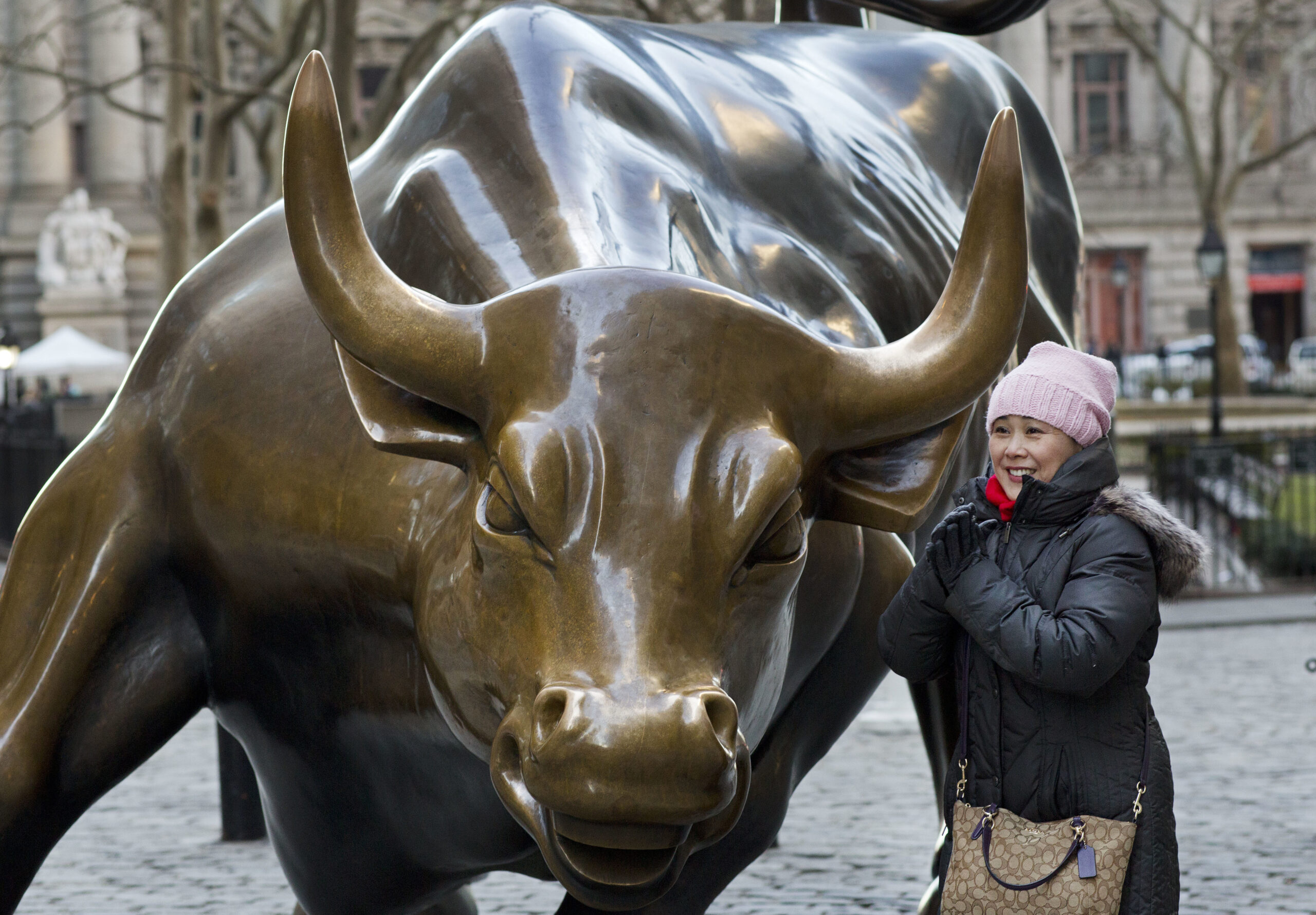 In this March 23, 2017 photo, a woman poses for photos with the Charging Bull statue in New York. Since 1989 the massive, bronze bull has stood in New York City's financial district as an image of the might and hard-charging spirit of Wall Street. (AP Photo/Mark Lennihan) (AP)