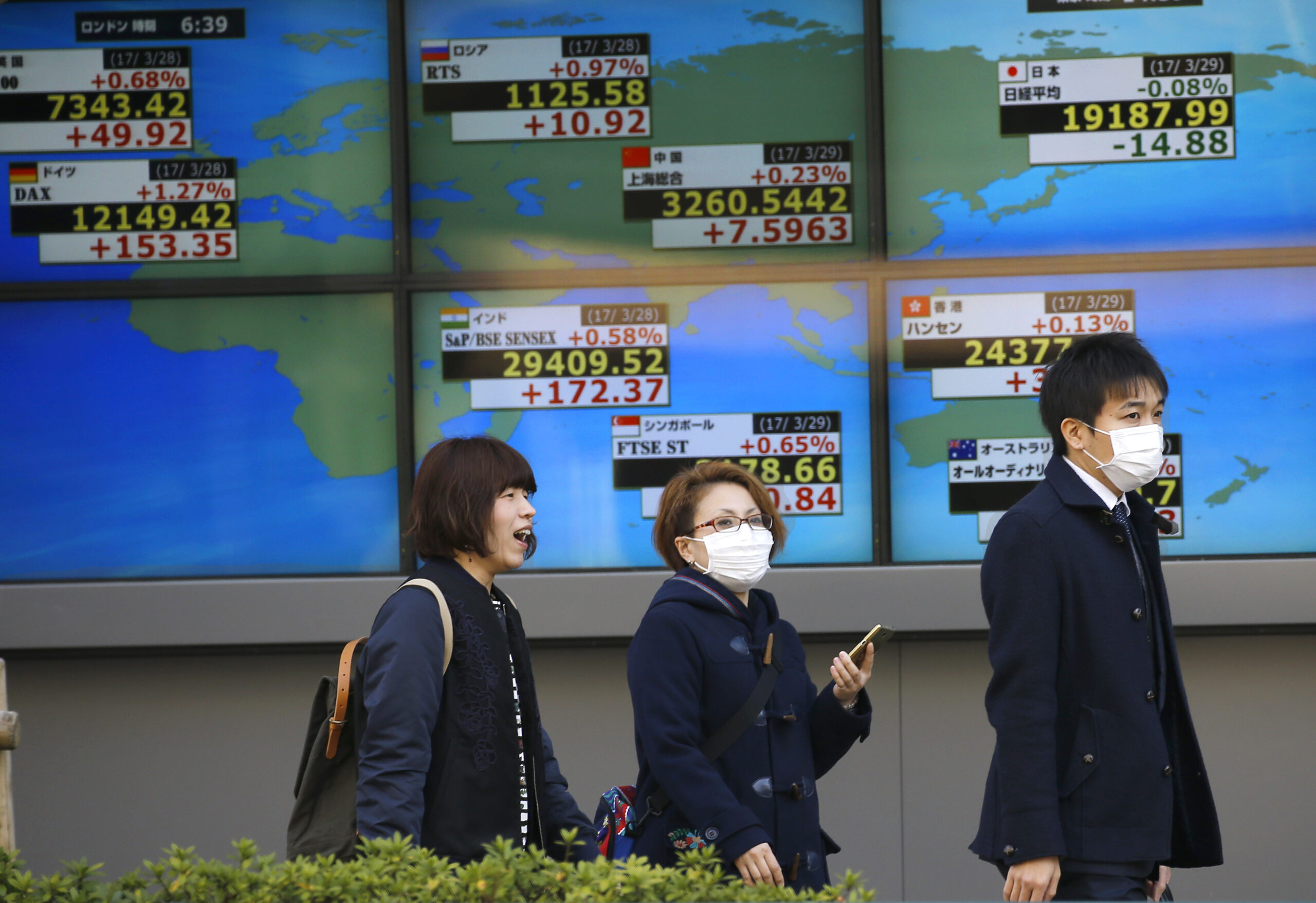 People walk past an electronic stock indicator of a securities firm in Tokyo, Wednesday, March 29, 2017. Asian stocks were listless Wednesday as investors weighed strong U.S. economic reports against uncertainty as Britain readies a formal request to leave the European Union. (AP Photo/Shizuo Kambayashi) (AP)