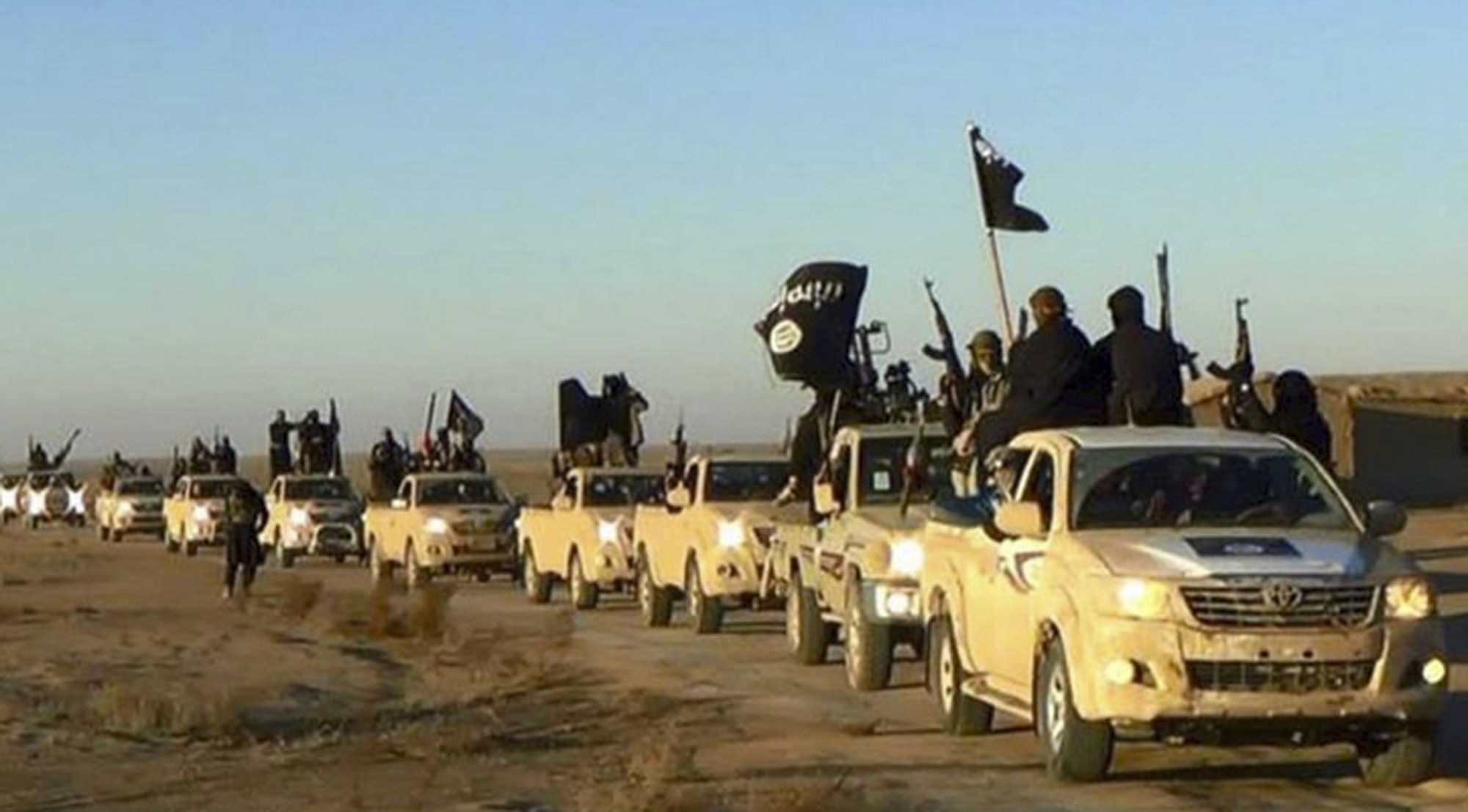 FILE - In this undated file photo released by a militant website, which has been verified and is consistent with other AP reporting, militants of the Islamic State group hold up their weapons and wave flags on their vehicles, in a convoy on a road leading to Iraq, from Raqqa, Syria. (AP)