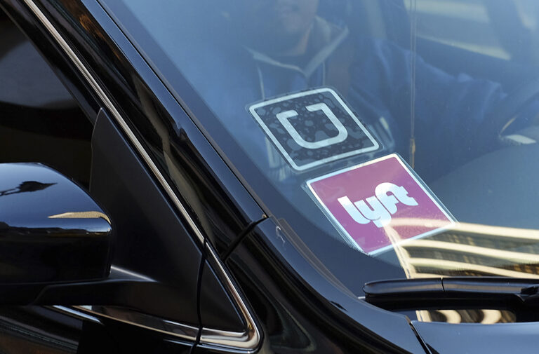 FILE - In this Tuesday, Jan. 12, 2016, file photo, a driver displaying Lyft and Uber stickers on his front windshield drops off a customer in downtown Los Angeles. (AP Photo/Richard Vogel, File)