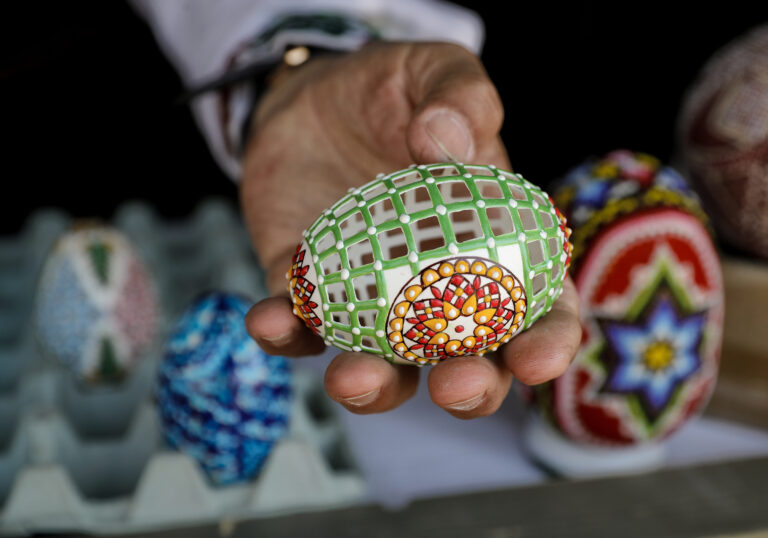 In this Thursday, April 13, 2017, picture artisan Nicu Poenariu displays for a photograph an Easter egg on sale at a fair in Bucharest, Romania. Ahead of Easter, celebrated by both Orthodox and Catholic believers on April 16 processions of priests clad in golden robes carrying foliage on Palm Sunday in a recreation of Jesus' ride into Jerusalem, mixed with more commercial flavored celebrations like an Easter fair outside the giant palace built by late Communist leader Nicolae Ceausescu where entertainers strutted around wearing giant rabbit heads.(AP Photo/Vadim Ghirda) (AP)