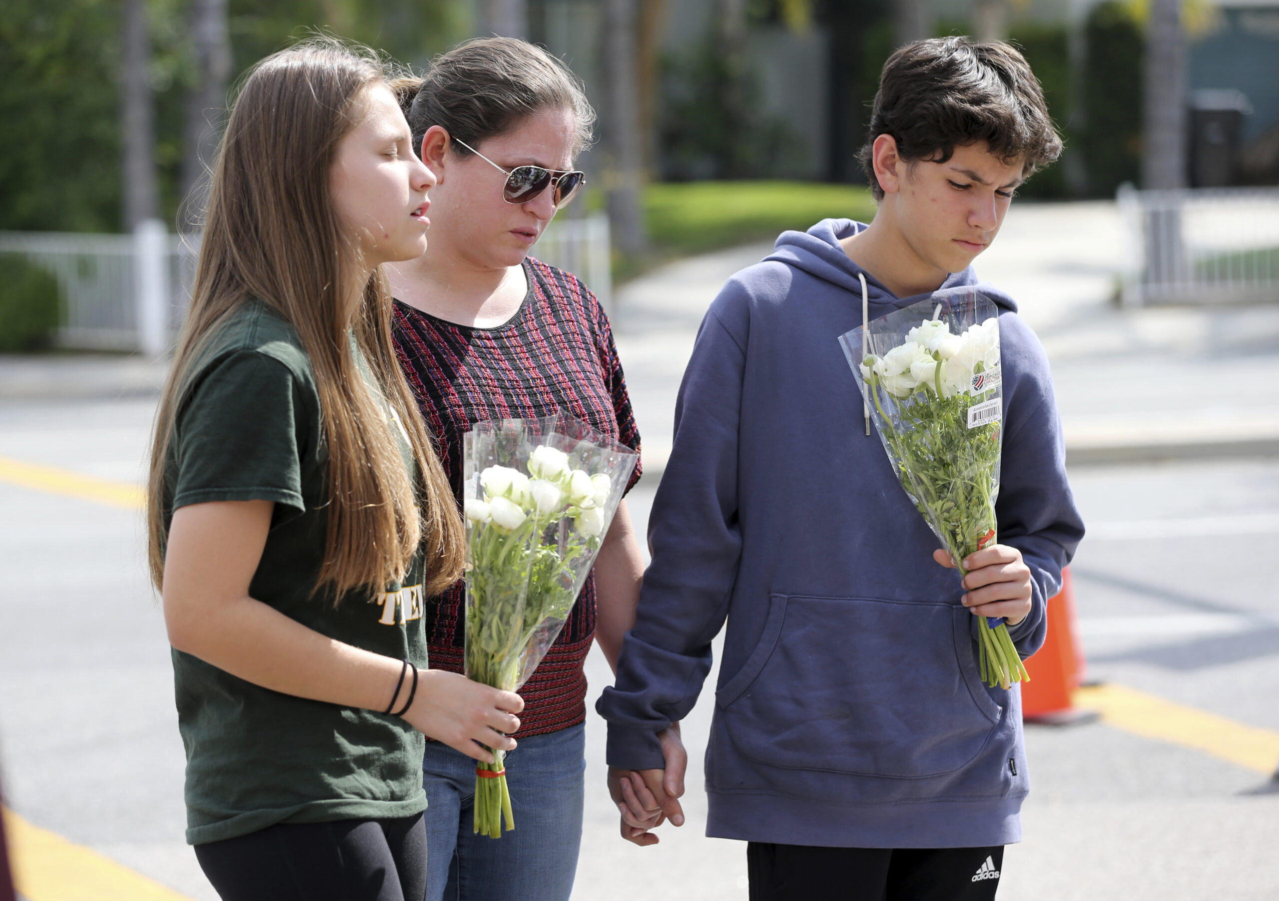 People pray before placing flowers at a sidewalk memorial to the teacher and student who were shot to death Monday at North Park Elementary School in San Bernardino, Calif., Tuesday, April 11, 2017. (AP Photo/Reed Saxon) (AP)