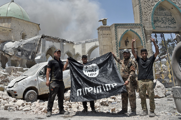 Members of the Iraqi Counter-Terrorism Service (CTS) hold upside-down the flag of the Islamic State (IS) group, in the Old City of Mosul, June 30, 2017. (Getty/Fadel Senna)