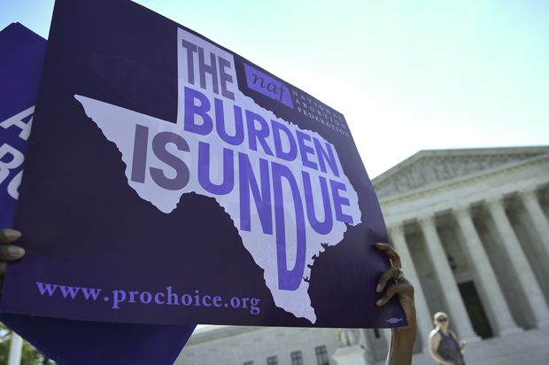 An abortion rights activist holds placards outside of the US Supreme Court before the Court struck down a Texas law placing restrictions on abortion clinics on June 27, 2016 in Washington, DC. (Getty/Mandel Ngan)
