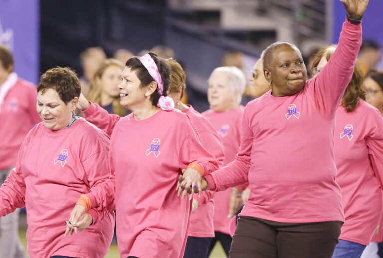 Breast cancer survivors walk on the field before an NFL game (AP/Seth Wenig)