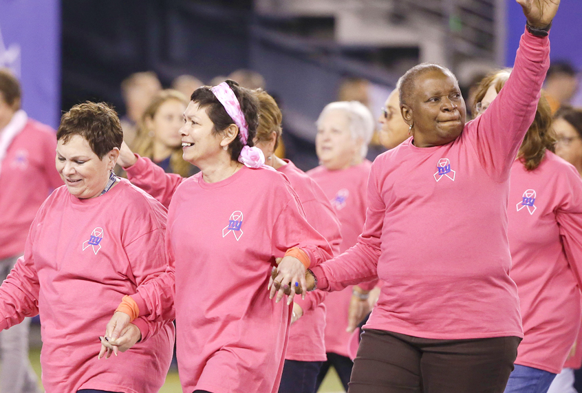 Breast cancer survivors walk on the field before an NFL game (AP/Seth Wenig)