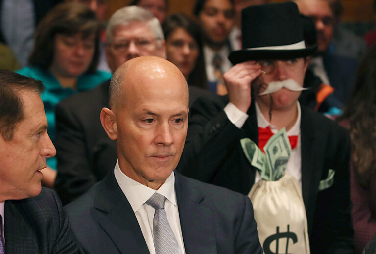 A man, right, dresses as the Monopoly Man at former Equifax CEO Richard Smith's testimony. (Getty/Mark Wilson)