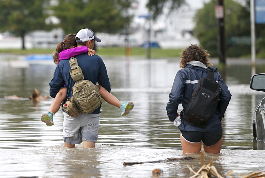 A family walk through a flooded roadway in the West End section of New Orleans (AP/Gerald Herbert)