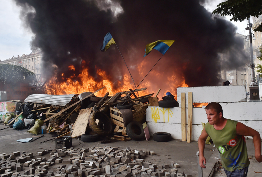 A man runs in front of a barricade burned by Maidan self-defence activists as they clash with residents of Kiev on August 9, 2014. (Getty/Sergei Supinsky)