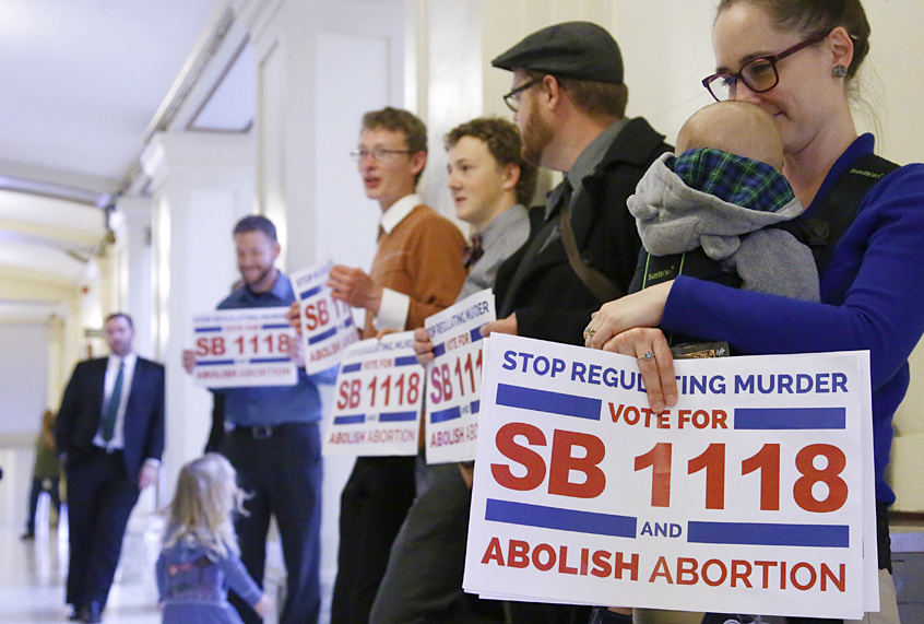 Anti-abortion activists stand outside the Oklahoma Senate chambers urging lawmakers to hear an anti-abortion measure that would make it a felony crime to perform an abortion (AP/Sue Ogrocki)