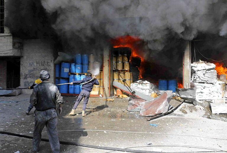Members of the Syrian Civil Defense group extinguishing a store during airstrikes and shelling by Syrian government forces, in Ghouta, Syria. (Syrian Civil Defense White Helmets via AP)