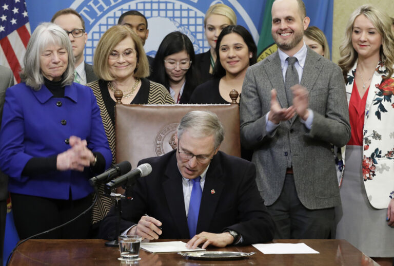 Washington Gov. Jay Inslee signs a bill March 5, 2018, that makes Washington the first state to set up its own net-neutrality requirements. (AP/Ted S. Warren)