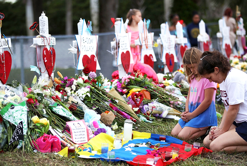 People visit a memorial in front of Marjory Stoneman Douglas High School. (Getty/Joe Raedle)