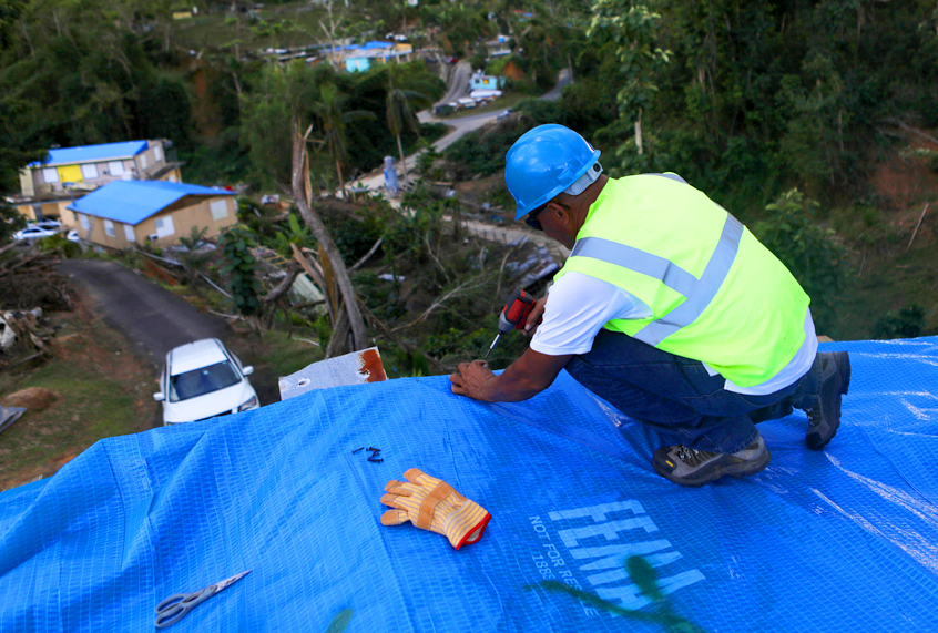 A contractor helps apply a FEMA tarp to a home damaged by Hurricane Maria in Morovis, Puerto Rico. (Getty/Mario Tama)