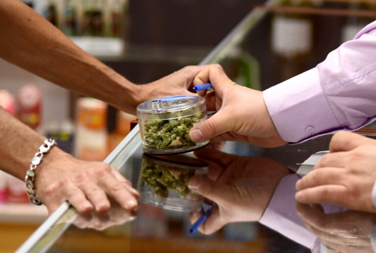 A budtender (right) shows cannabis buds to a customer at the Green Pearl Organics dispensary on the first day of legal recreational marijuana sales in Desert Hot Springs, California. (Getty/Robyn Beck)