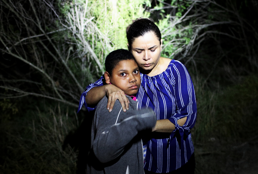 A U.S. Border Patrol spotlight shines on a terrified mother and son from Honduras as they are found in the dark near the U.S.-Mexico border in McAllen, Texas. (Getty/John Moore)